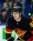 Hockey player in black, red, and yellow uniform with visible branding on a blurred background