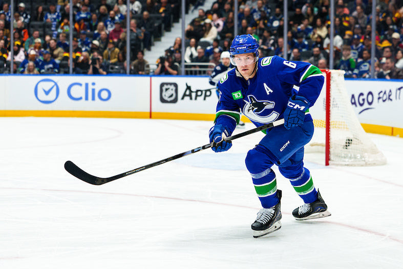 Hockey player in blue uniform on ice rink with spectators and advertisements in the background