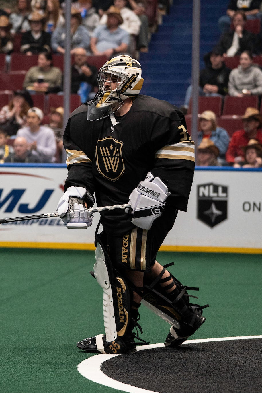 Lacrosse player in action on a field with spectators in the stands.
