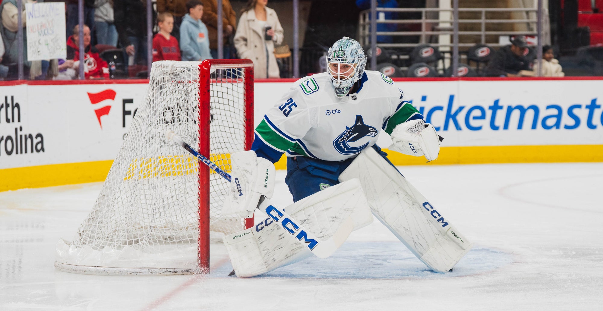 Hockey goalie in action on an ice rink with advertisements in the background