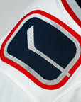 Close-up of a sports jersey with a logo featuring a hockey stick and puck.