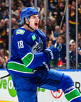 Hockey player in blue uniform with number 18 on ice rink, surrounded by spectators.