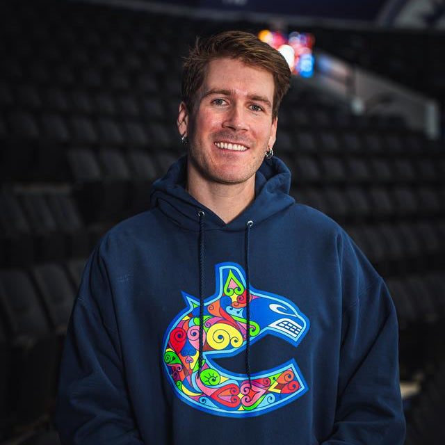 Person wearing a blue hoodie with a colorful logo in an indoor setting